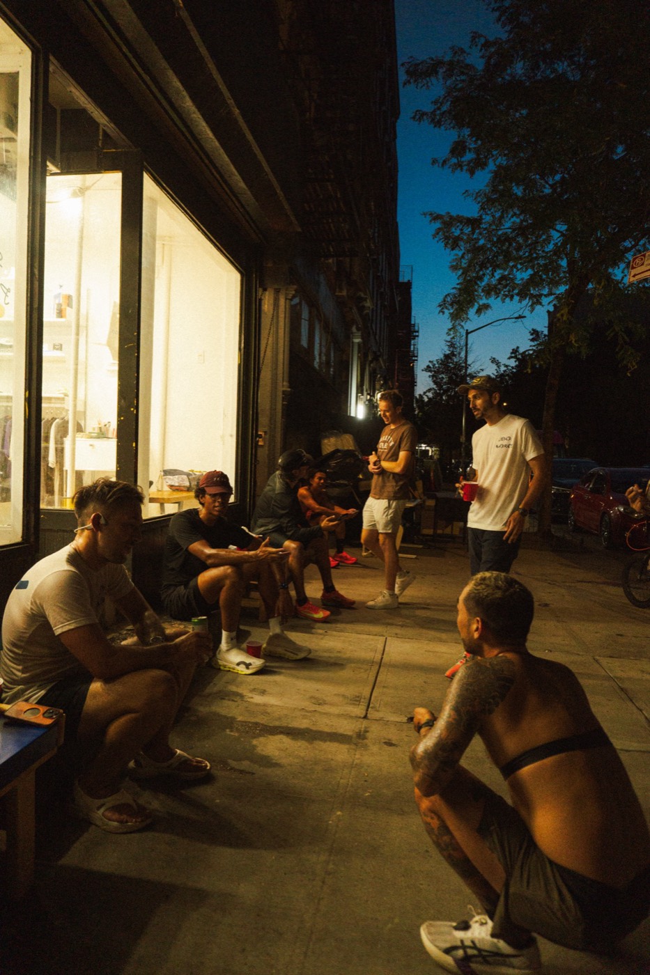 Runners gathered on a sidewalk at night after Supermarket Race 1