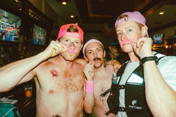 Three runners in pink hats with pink mustaches after The Warriors 2026