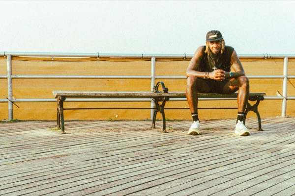 A runner resting on a Coney Island boardwalk bench at The Warriors 2026