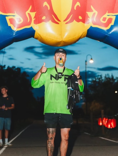 A runner giving two thumbs up under the finish arch at the Vivo Midnight 25K/50K