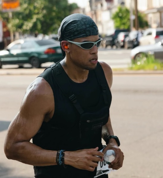 A runner in a bandana and wraparound sunglasses mid-stride with a water bottle at WEPA 9 for 9