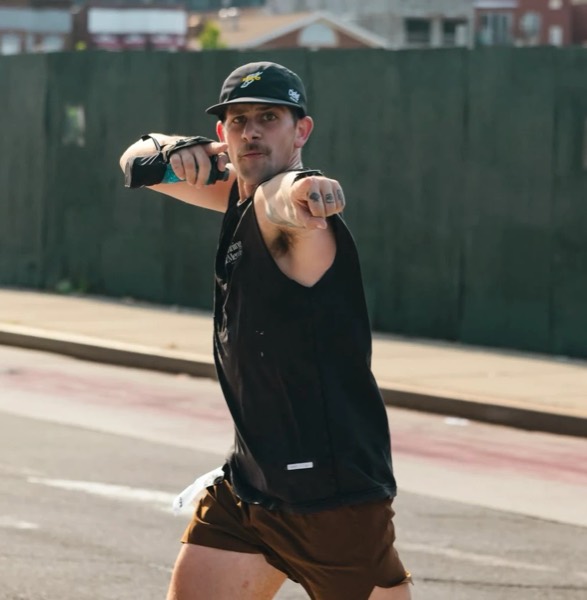 A runner in a cap pointing at the camera mid-race at WEPA 9 for 9